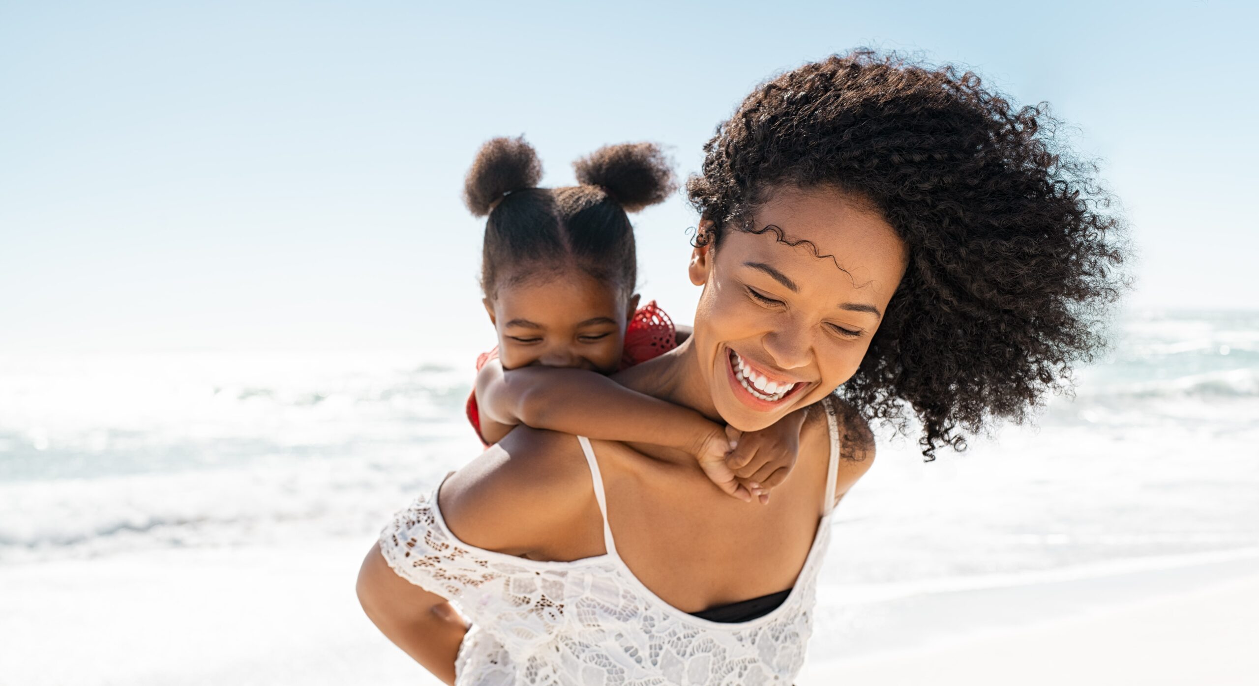 woman smiling while giving a child a piggyback ride