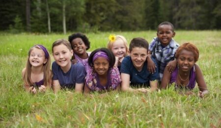 group of smiling kids laying in a grass field
