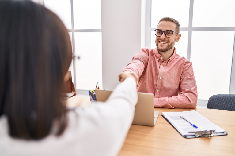businesspeople sitting at a table and shaking hands