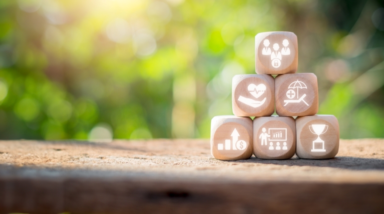 stack of wooden blocks with icons representing various benefits, such as paid vacation time
